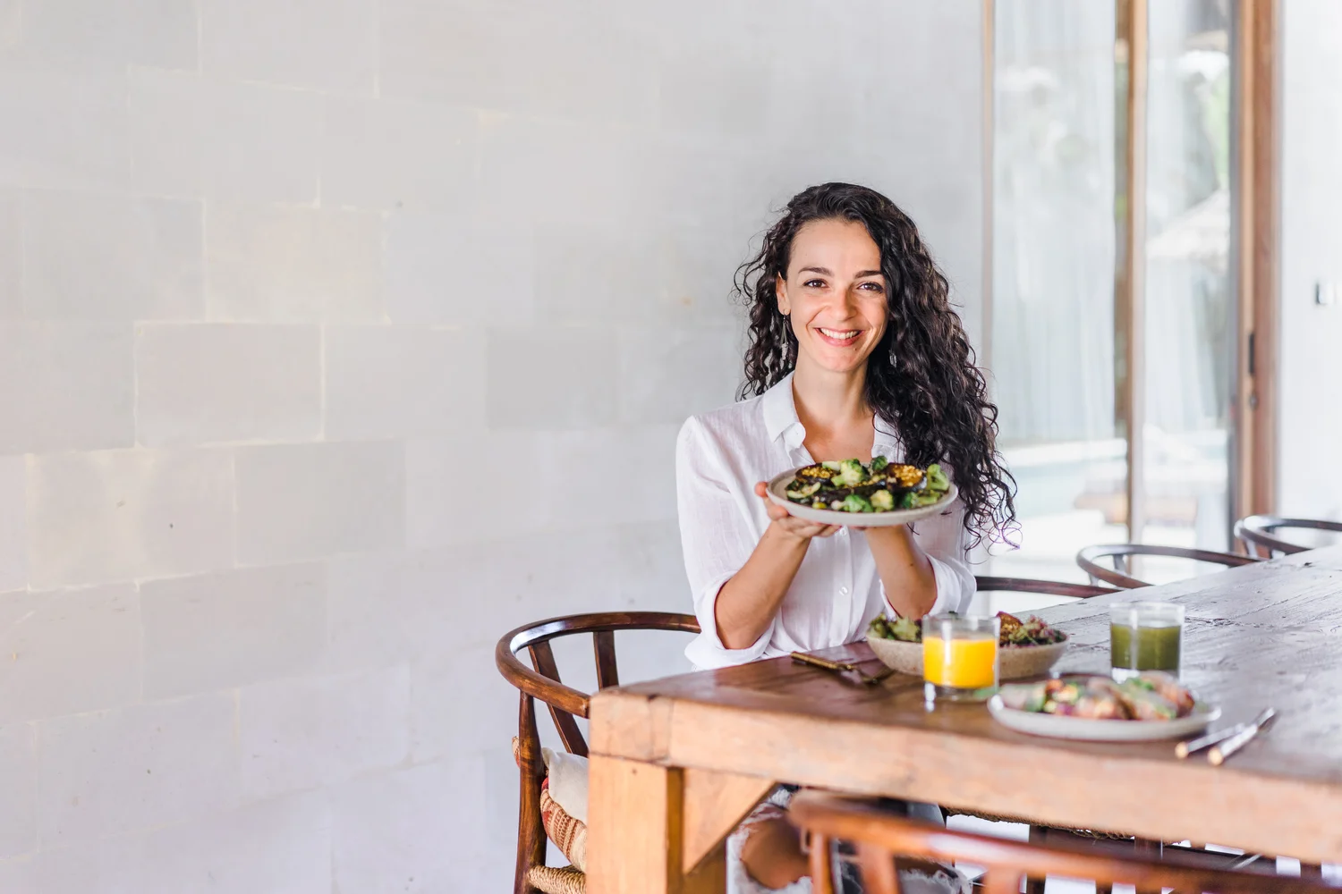 Sofia Konstantinidou, vegane Ernährungsberaterin, mit einem Teller mit gebackenem Gemüse und Salat