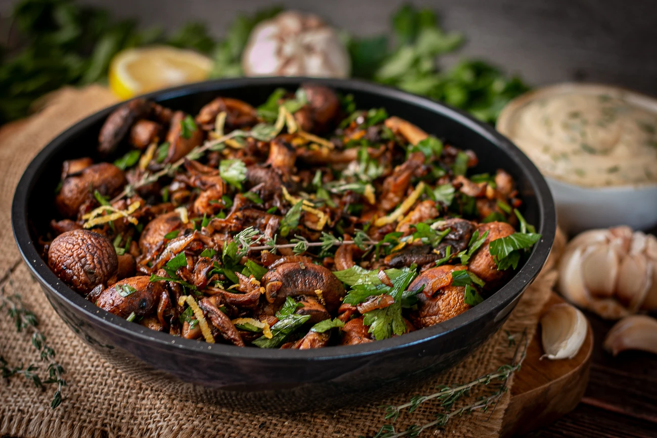 Pilzpfanne mit Knoblauchdip - vegan & lecker Goldbraun gebratene Champignons und Austernpilze mit Zwiebeln, Thymian und Petersilie in einer schwarzen Pfanne